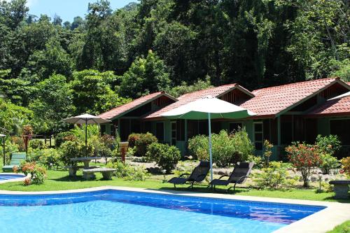 a house with a pool and chairs and an umbrella at Hacienda Baru in Dominical