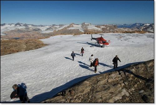 a group of people walking in the snow with a helicopter at Hotel Angmagssalik in Tasiilaq