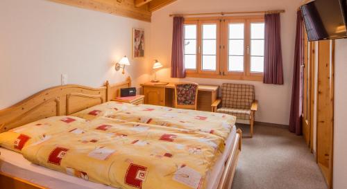 a bedroom with a bed and a desk and a chair at Familienhotel Garni Sporting in Bettmeralp