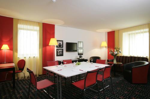 a dining room with a table and red chairs at Vienna House Easy by Wyndham Bucharest Airport in Otopeni