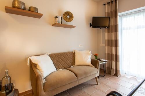 a living room with a couch and a tv at Landhotel Teichwiesenhof in Oldenburg in Holstein