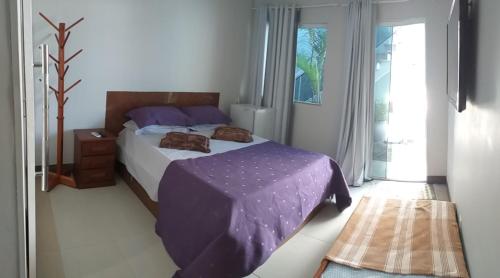 a bedroom with a bed with a purple comforter at Airport Pousada in Cabo Frio