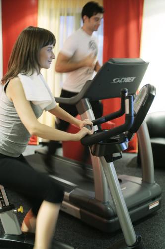a woman riding on a treadmill in a gym at Vienna House Easy by Wyndham Bucharest Airport in Otopeni