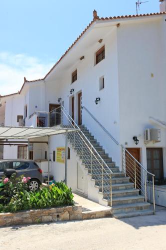 a white building with stairs and a car parked in front at Panormos Maisonettes in Panormos Skopelos
