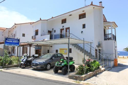 a building with a car and motorcycles parked in front of it at Panormos Maisonettes in Panormos Skopelos