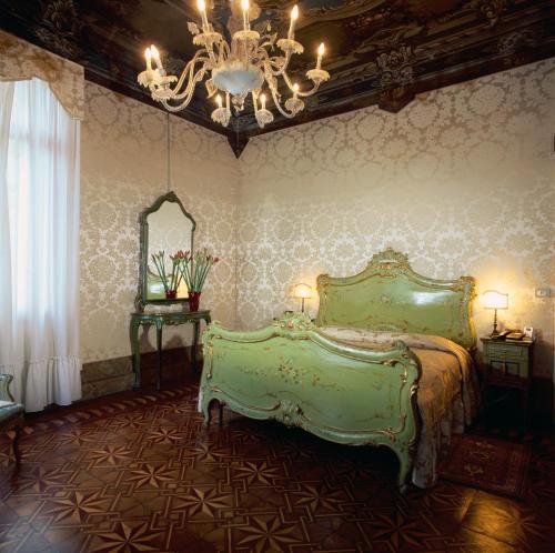 a bedroom with a green bed and a chandelier at Hotel Palazzo Abadessa in Venice