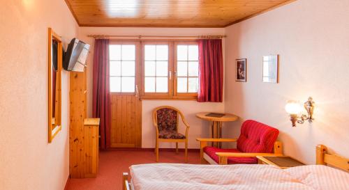 a bedroom with a bed and a chair and a table at Familienhotel Garni Sporting in Bettmeralp