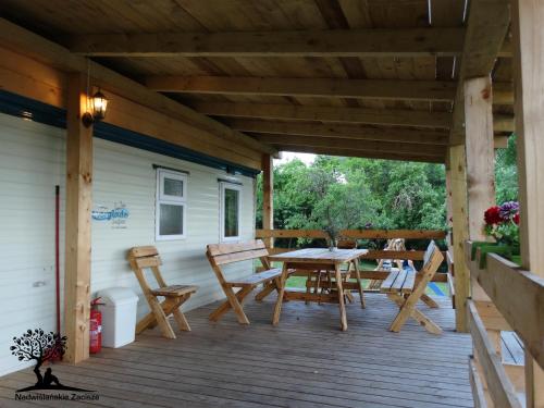 une terrasse couverte en bois avec une table et des chaises. dans l'établissement Nadwiślańskie Zacisze, à Kozielec