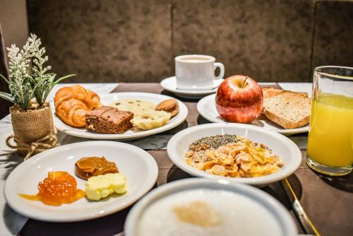 a table with plates of breakfast foods and an apple at Fuente Mayor Hotel Centro in Mendoza