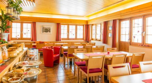 a restaurant with tables and chairs and windows at Familienhotel Garni Sporting in Bettmeralp