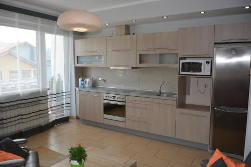 a kitchen with wooden cabinets and a stainless steel refrigerator at Apartament Maryla in Giżycko