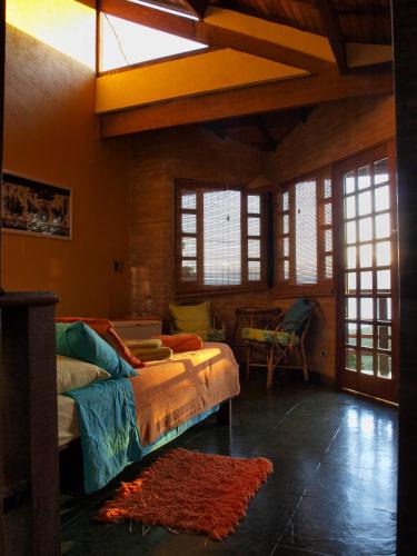 a living room with a bed in a room with windows at Pousada Casa Milà in Ubatuba