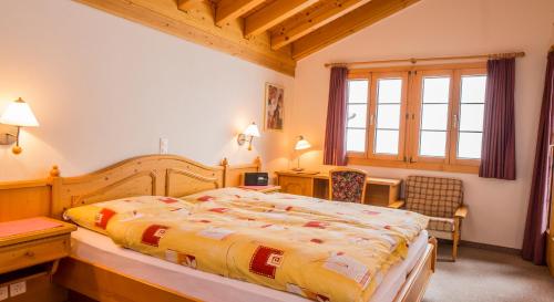 a bedroom with a bed and a desk and a window at Familienhotel Garni Sporting in Bettmeralp