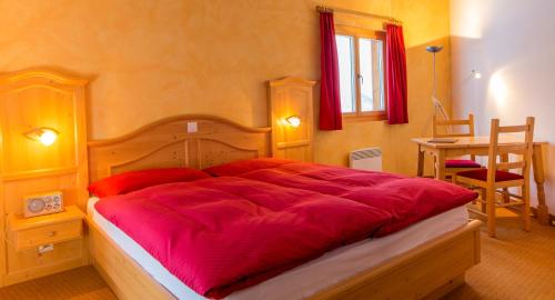 a bedroom with a large bed with red sheets at Familienhotel Garni Sporting in Bettmeralp