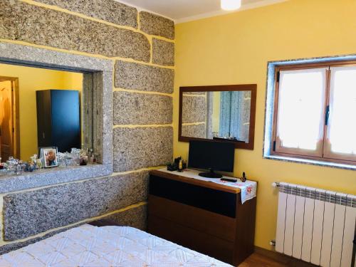 a bedroom with a stone wall with a bed and a mirror at Chambre de la tour - Quinta da Prelada Simão in Celorico de Basto