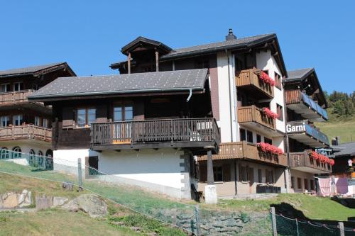 a large house with balconies on a hill at Familienhotel Garni Sporting in Bettmeralp