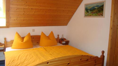 a bedroom with a wooden bed with yellow pillows at Mettenberger Hof - Pension in Grafenhausen