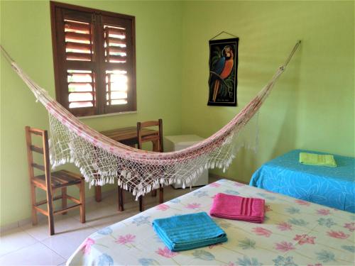 um quarto com uma rede de descanso num quarto com uma mesa em Pousada Muiraquitã em Beberibe