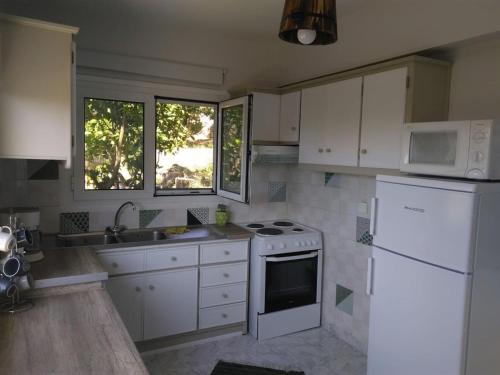 a kitchen with white cabinets and a white refrigerator at House with fruit trees, olive trees, and sea view. in Vathý
