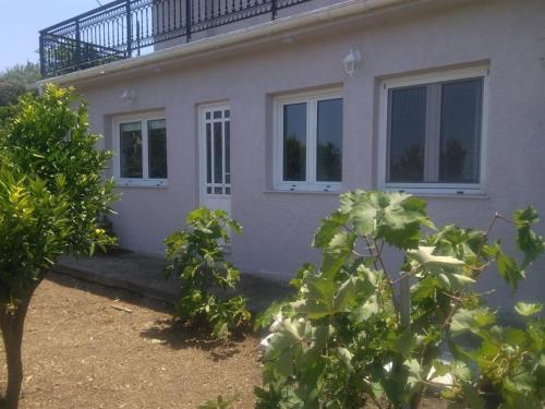 a house with a balcony on top of it at House with fruit trees, olive trees, and sea view. in Vathý
