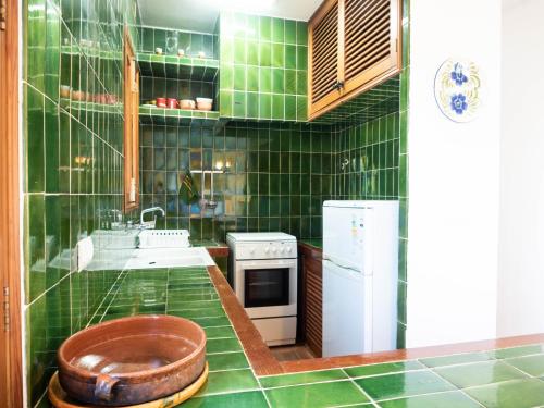 una cocina de azulejos verdes con un bol de madera en la encimera en Casa Sa Serreta, en Sant Ferran de Ses Roques