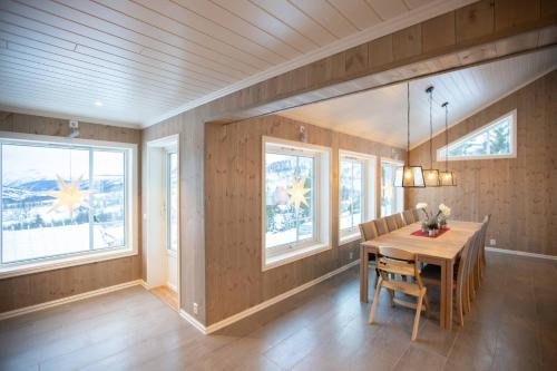 a dining room with a wooden table and windows at Rolfhytta - Fosskamben 19 in Sogndal