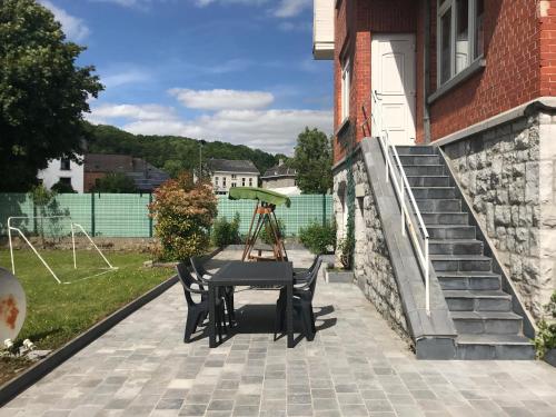 a patio with a table and chairs and a building at Voisins du kayak in Dinant