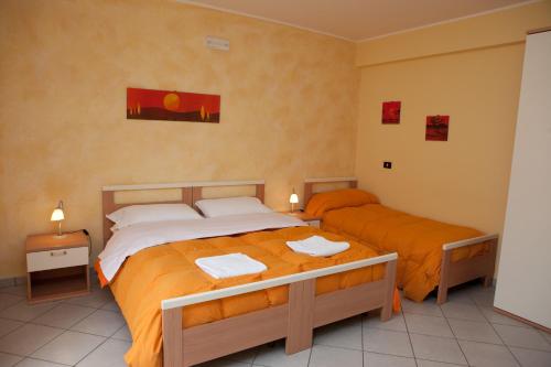 two beds in a bedroom with orange sheets at B&B Casa Mauro in Linguaglossa