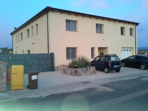 a building with two cars parked in front of it at B&B S'Ena in Suni