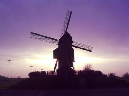 a windmill with the sun setting in the background at Orchidee Premium in Comines