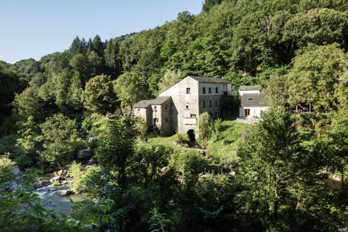 une vieille maison sur une colline à côté d'une rivière dans l'établissement Moulin de Record, à Ferrières