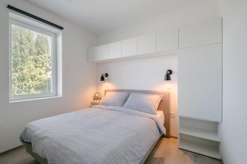 a white bedroom with a bed and a window at Apartment Fresh - Parking included in Izola