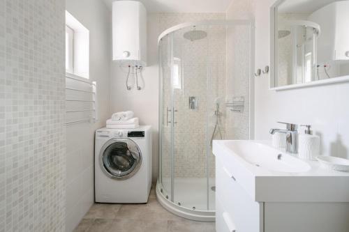 a white bathroom with a washing machine and a sink at Apartment Fresh - Parking included in Izola