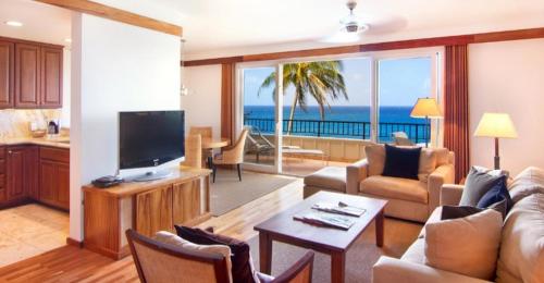 a living room with a television and a living room with the ocean at Whalers Cove in Poipu in Koloa