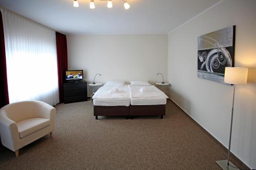 a bedroom with a bed and a chair and a television at Appartementanlage Vierjahreszeiten in Braunlage