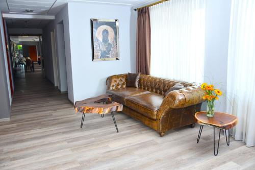 a living room with a brown leather couch and a table at LANDHAUS LENGEDE Hotel in Lengede