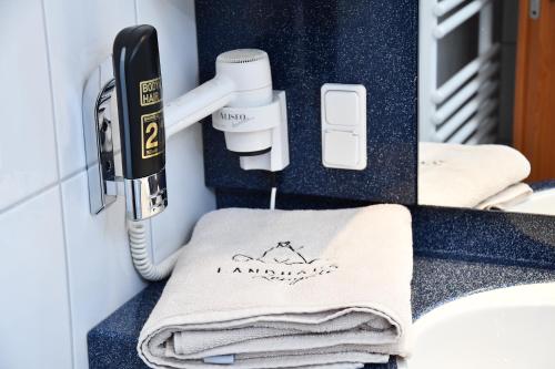 a bathroom with a phone and towels on a counter at LANDHAUS LENGEDE Hotel in Lengede