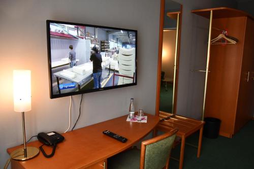 a room with a tv on a wall with a table at LANDHAUS LENGEDE Hotel in Lengede