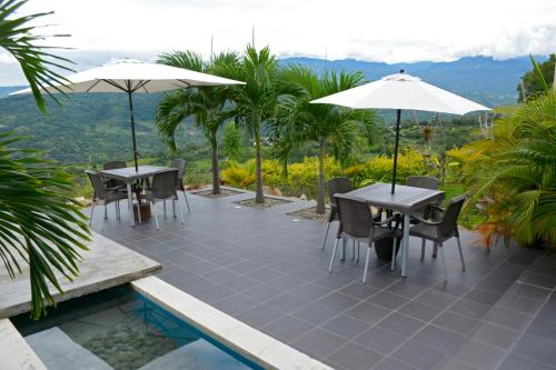 a patio with tables and chairs and umbrellas at Gyrola Birding Hotel Boutique in La Mesa