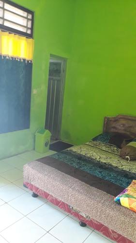 a green room with two beds and a window at Willy Homestay Borobudur in Borobudur