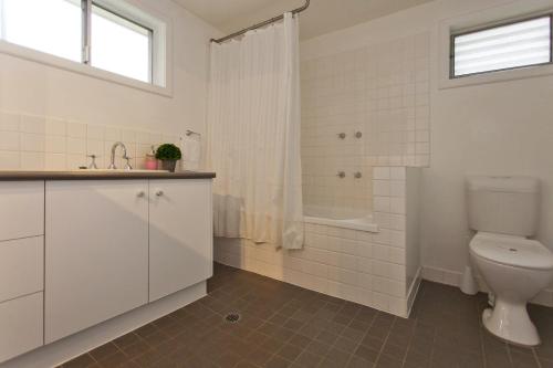 Un baño blanco con inodoro y ducha. en Red Brick Beauty - Central Cottage, en Albury