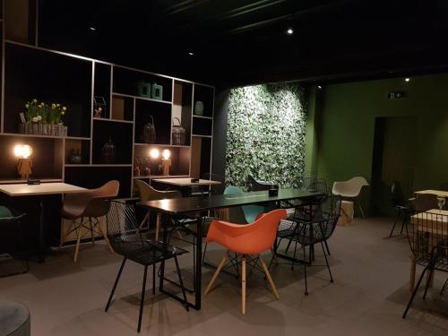 a dining room with tables and chairs and a green wall at bosbAAr in Kluisbergen