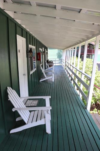 a green porch with two white chairs on it at Lone Fir Resort in Cougar