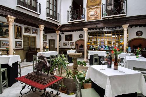 a restaurant with white tables and a statue in the middle at Casa Palacio Pilar del Toro in Granada