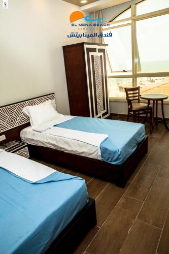 two beds in a room with a table and chairs at El Mena Beach in Ras El Bar