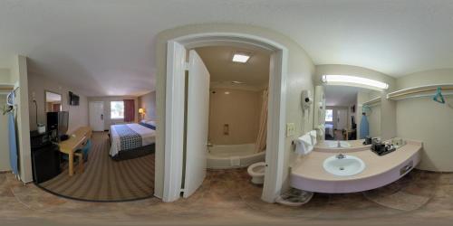 een badkamer met een wastafel, een bad en een bed bij River Inn Motel in San Antonio