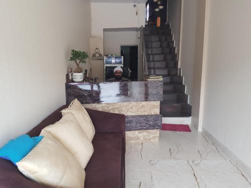 a man standing in a living room with a couch at Backpackers Villa Mumbai in Mumbai
