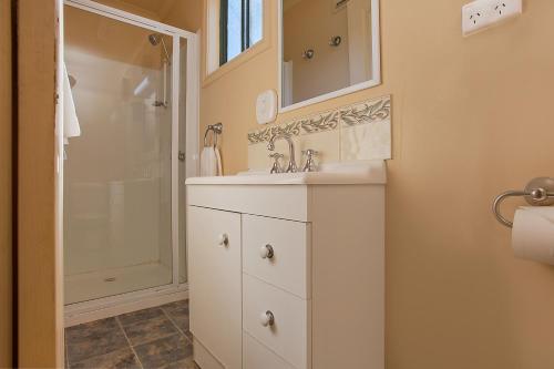 a white bathroom with a sink and a shower at Hamilton Caravan Park in Hamilton