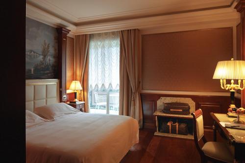 a bedroom with a bed and a desk and a window at Hotel Splendid in Baveno