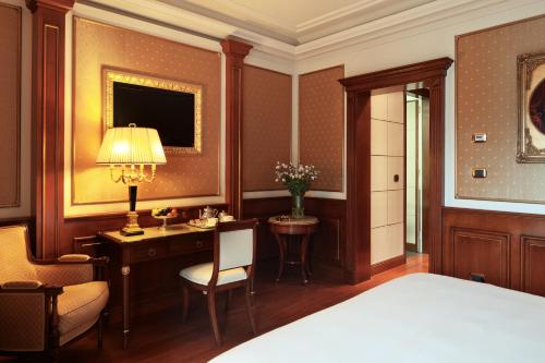 a bedroom with a bed and a desk with a lamp at Hotel Splendid in Baveno